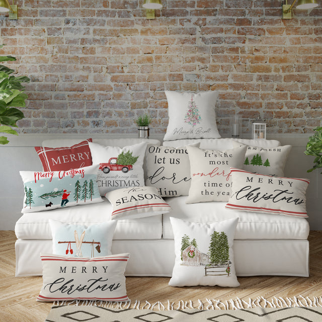 Collection of Christmas-themed pillows on a sofa against a brick wall.