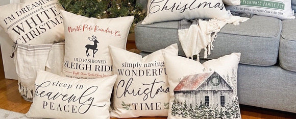 Decorative Christmas pillows on a couch with a Christmas tree in the background