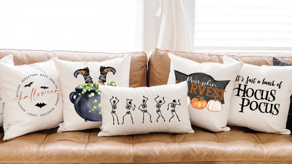 Halloween-themed decorative pillows on a brown sofa with a white curtain in the background.