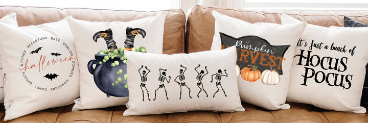 Halloween-themed decorative pillows on a brown sofa with a white curtain in the background.