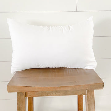 White rectangular faux-down pillow insert on a wooden stool