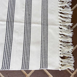 White with black vertically grouped stripes entry rug displayed on porch closeup