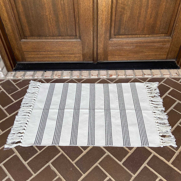 White with black vertically grouped stripes entry rug displayed on porch