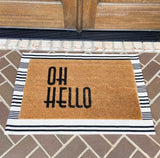 White and black horizontal stripe entry rug displayed on porch under grass door mat